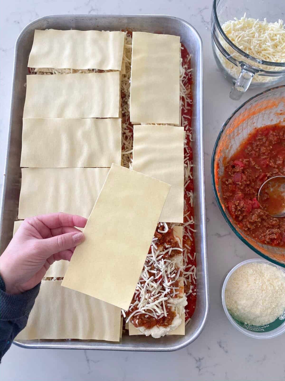 layering homemade lasagna in pan