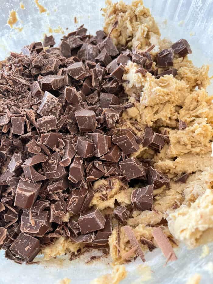 chocolate chunks added to cookie dough in mixing bowl