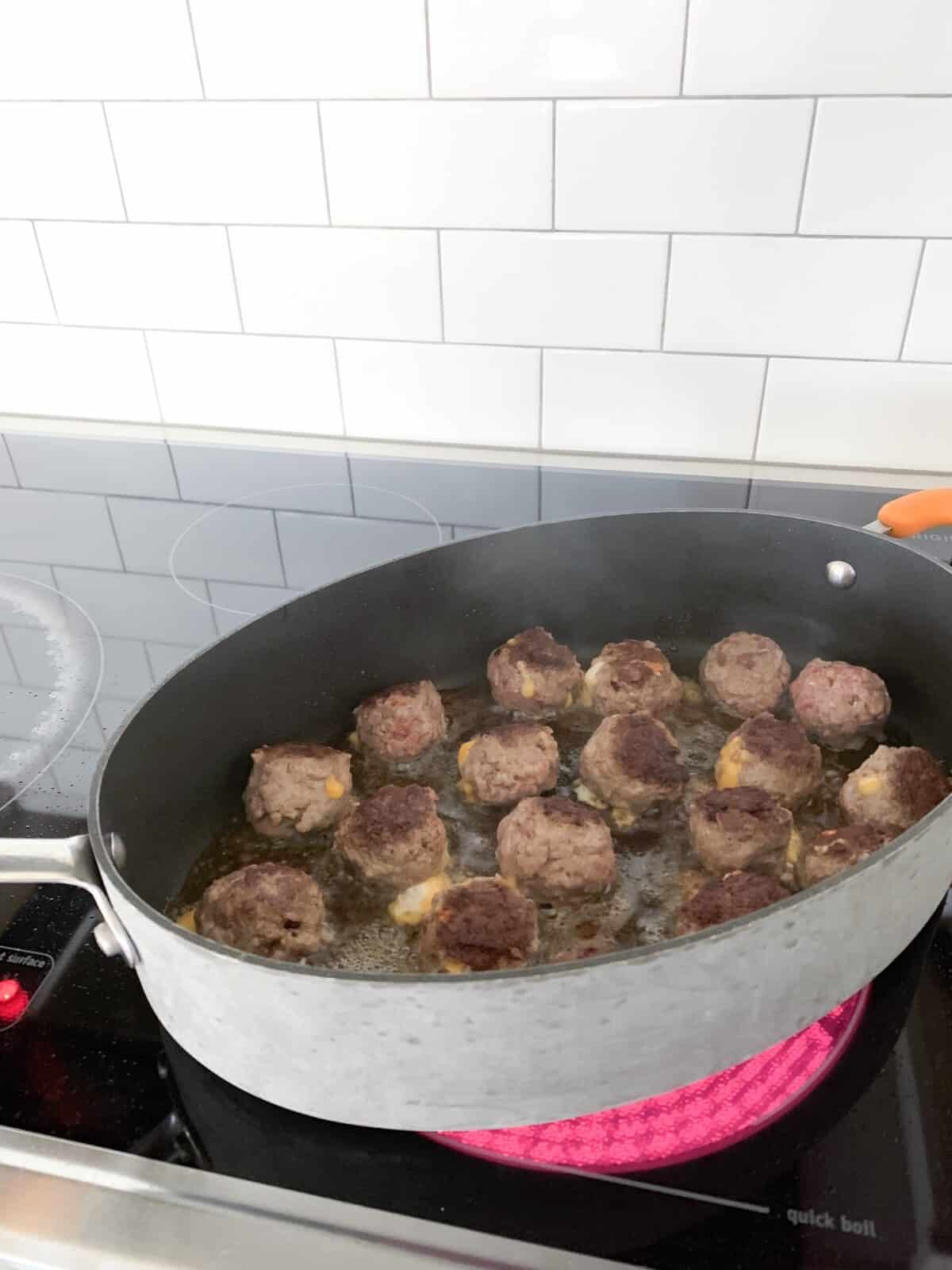 homemade meatballs cooking in pan