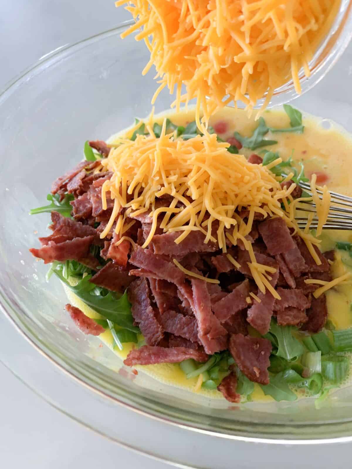 adding cheese to egg mixture in mixing bowl