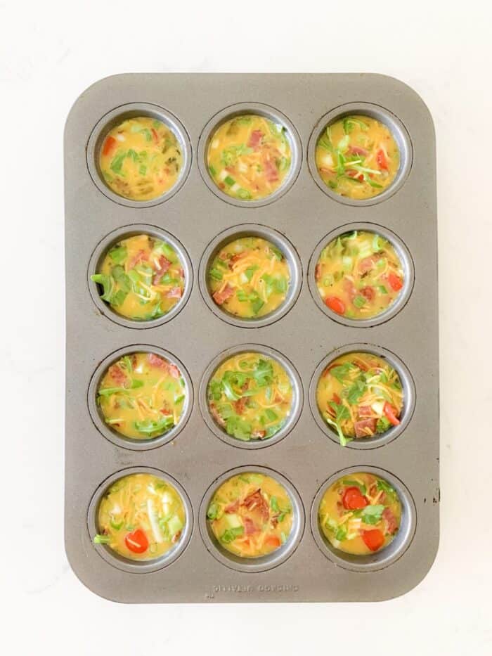 egg bites recipe filled in muffin tin ready to bake
