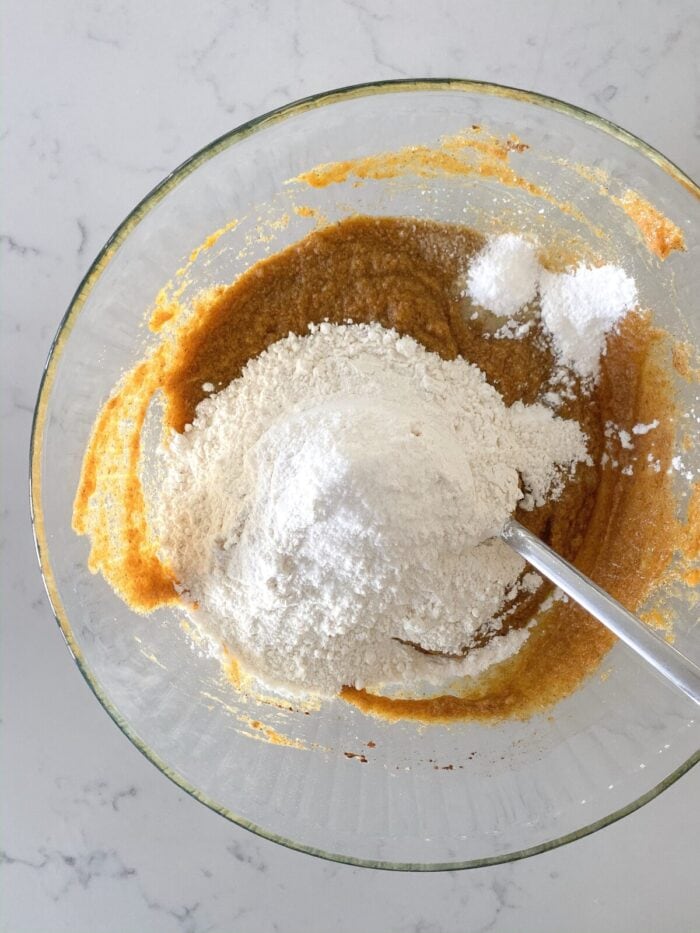 adding dry ingredients to mixing bowl for soft pumpkin cookies