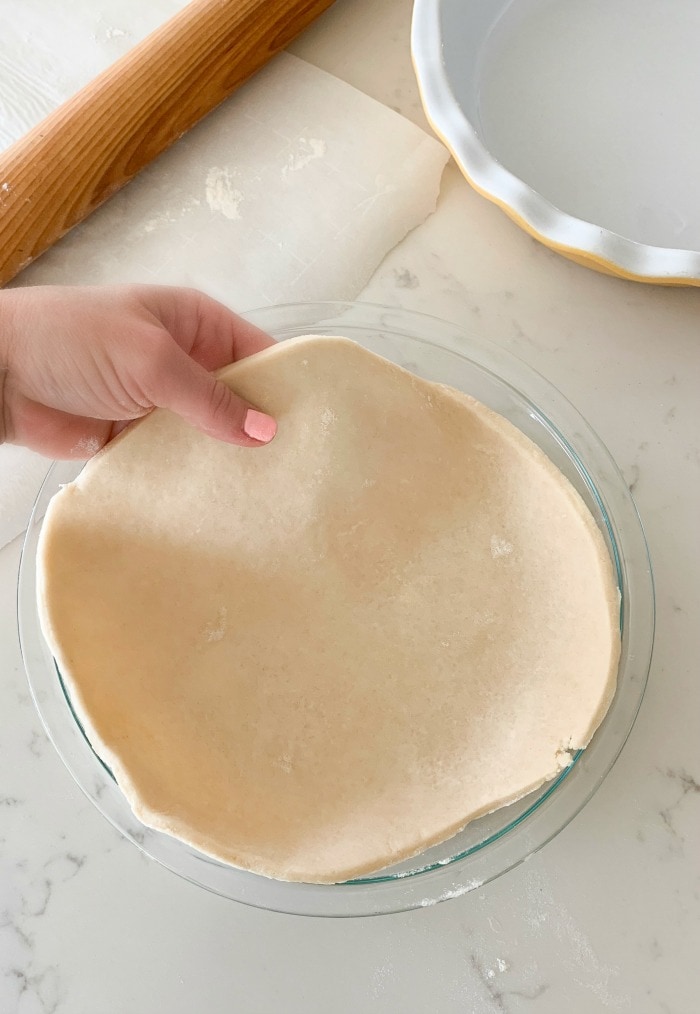 adding rolled pie dough to pie pan