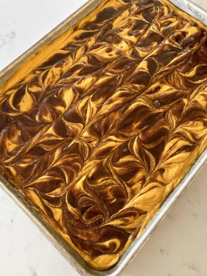 swirling cinnamon roll mixture into pumpkin sheet cake