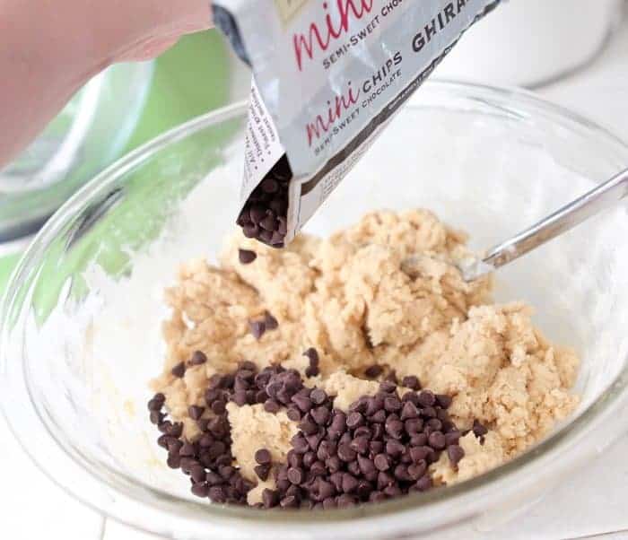 adding chocolate chips to bowl of cookie dough
