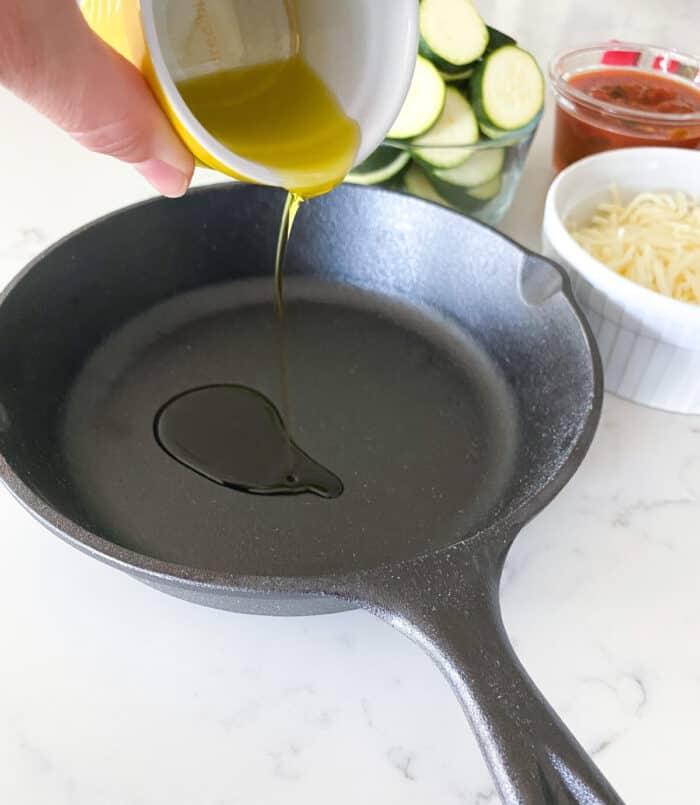 pouring olive oil in cast iron skillet