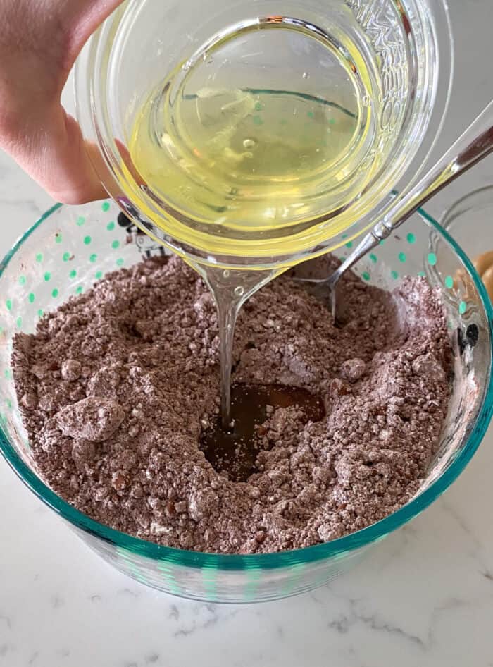 adding oil to flourless cookie dough in mixing bowl