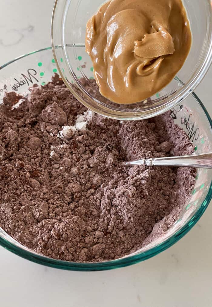 adding peanut butter to flourless cookies in mixing bowl