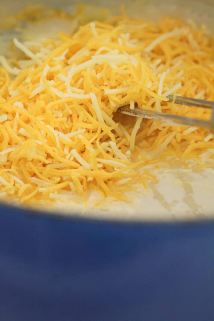 adding cheese to cheese sauce