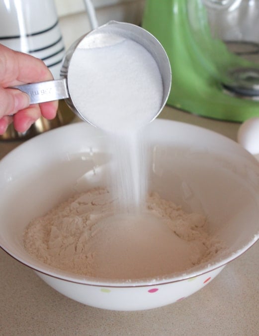 adding dry ingredients for waffle recipe in mixing bowl