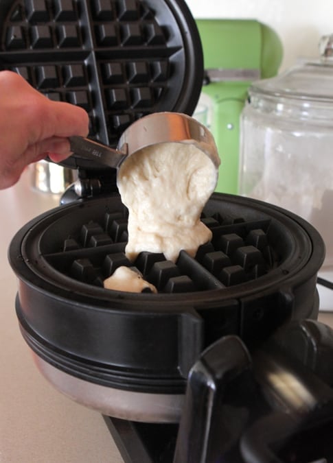pouring waffle batter into hot waffle iron