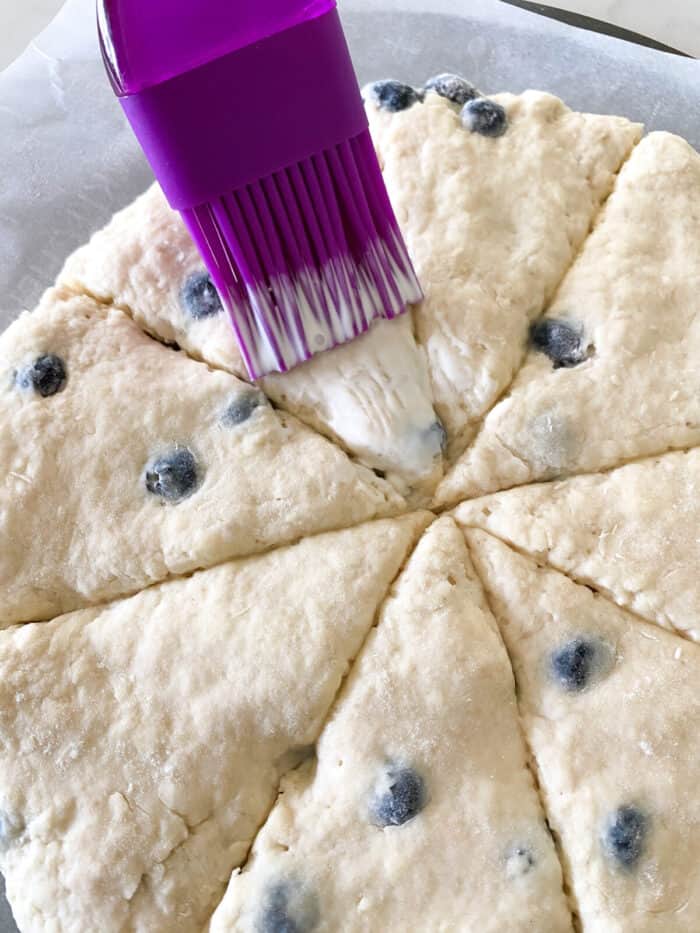 brushing scone dough with heavy cream before baking