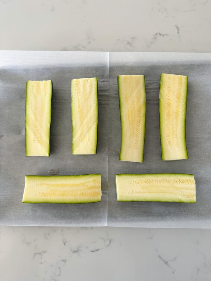 zucchini cut in half length wise with ends cut off on baking sheet