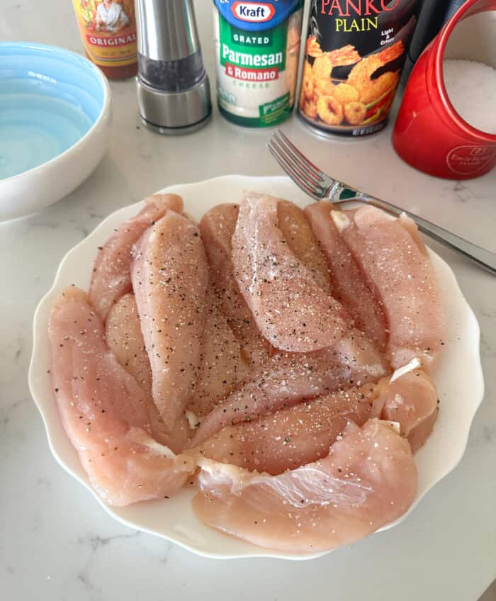 chicken tenders on a plate seasoned with salt and pepper