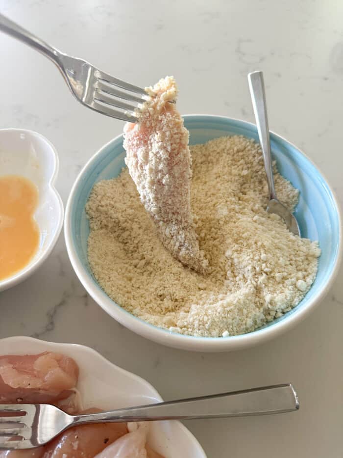 dipping chicken tender in panko and parmesan