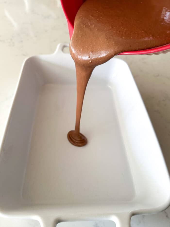 pouring chocolate cake batter into pan