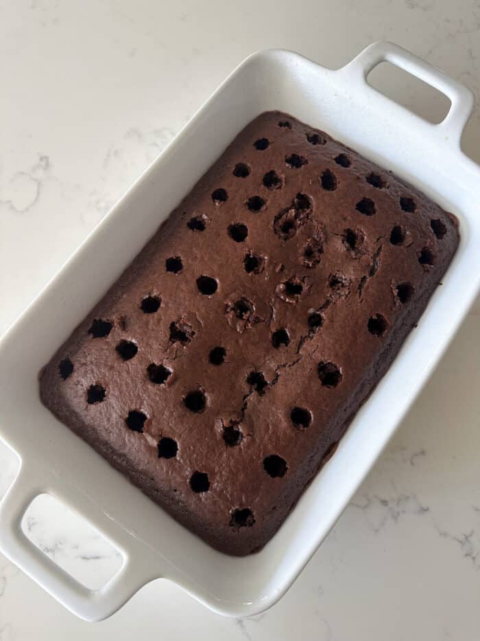 devils food cake baked in pan with holes poked in cake