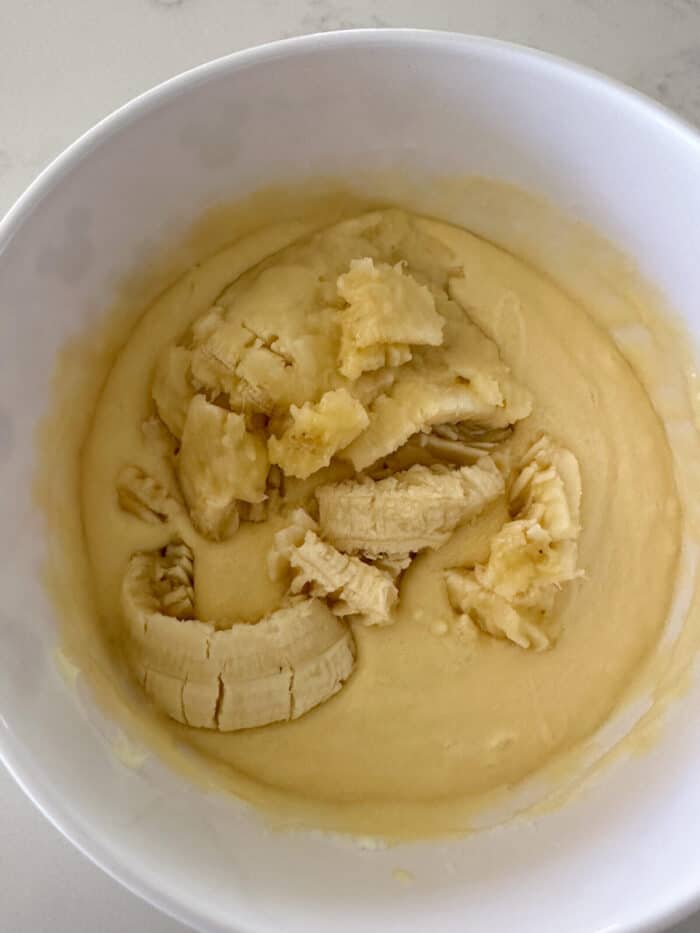 mashed banana added to mixing bowl with wet ingredients