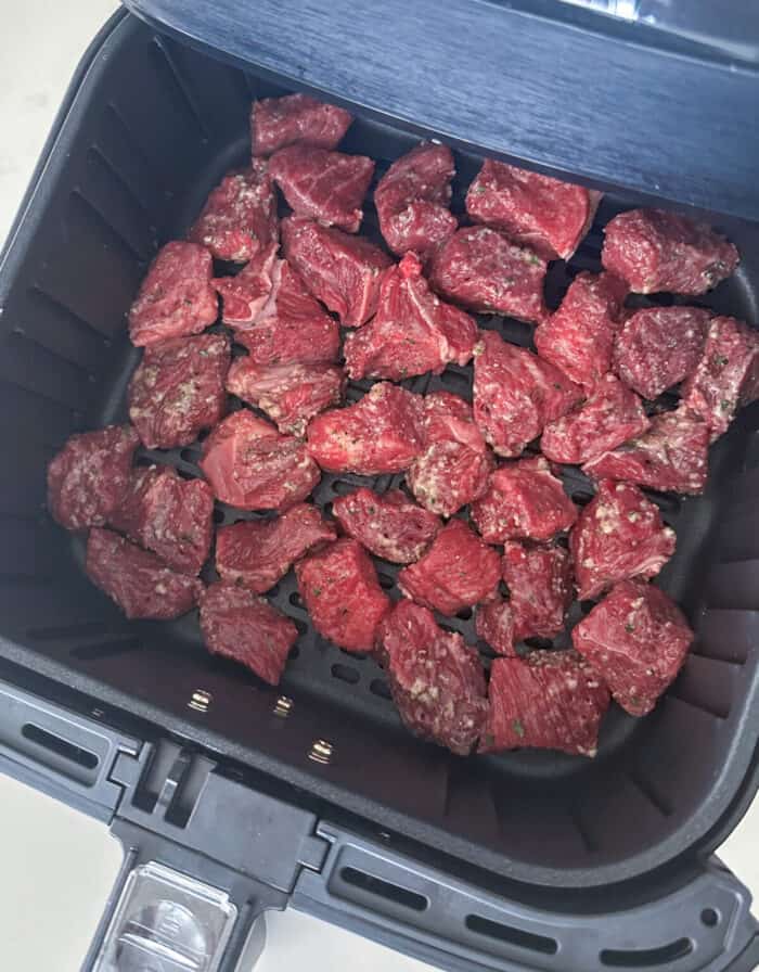 steak bites in air fryer basket ready to cook