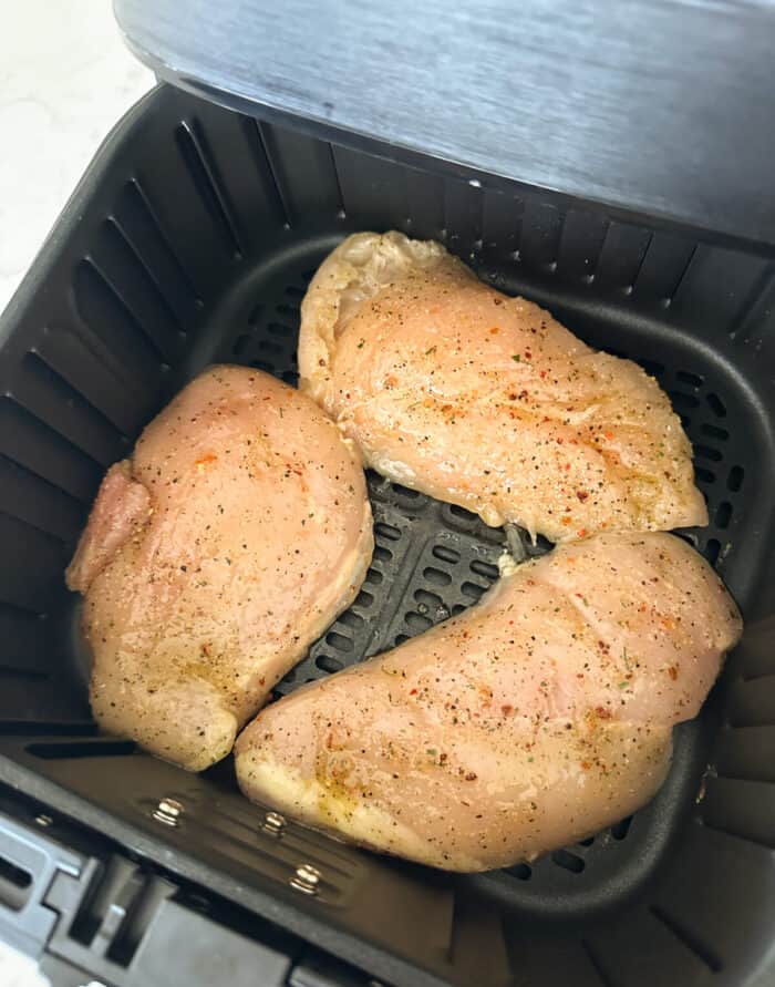 raw chicken breast inside basket of air fryer