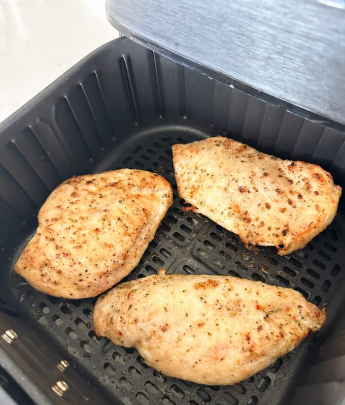 cooked chicken breast inside basket of air fryer