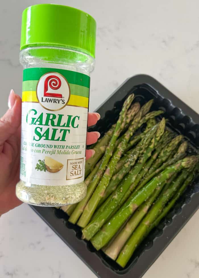 adding garlic salt to asparagus