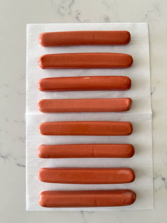 uncooked hot dogs removed from package on counter top.