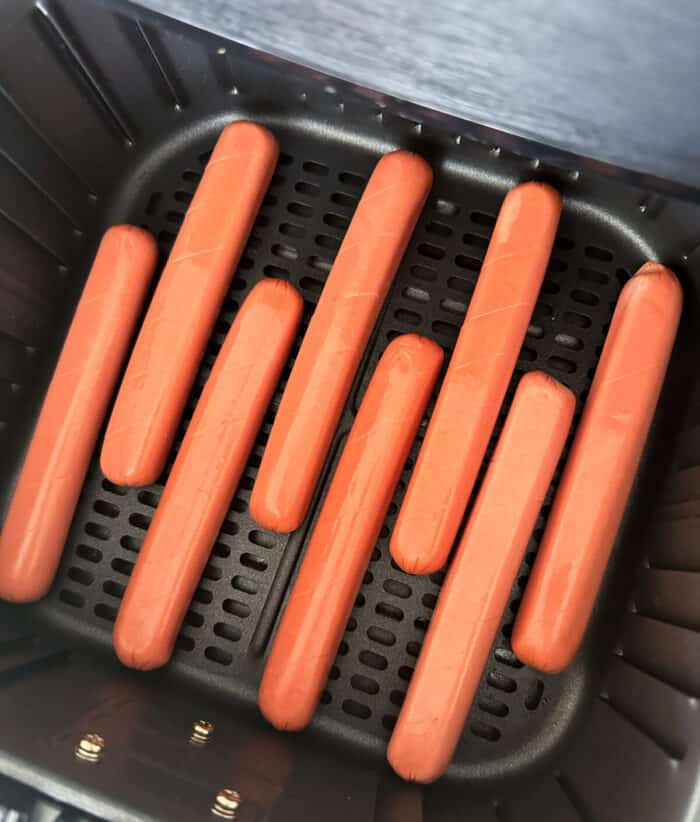 uncooked hot dogs in air fryer basket