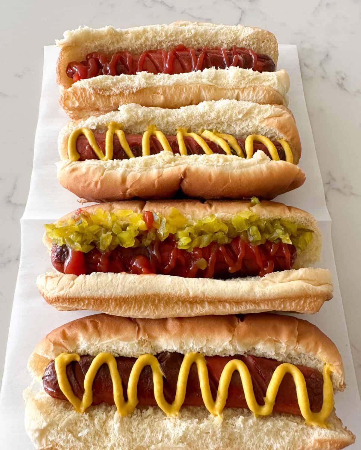 hot dogs in buns with ketchup and mustard on counter