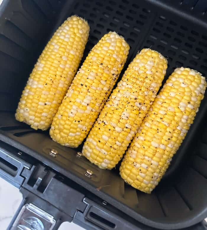 corn on the cob inside air fryer basket ready to cook