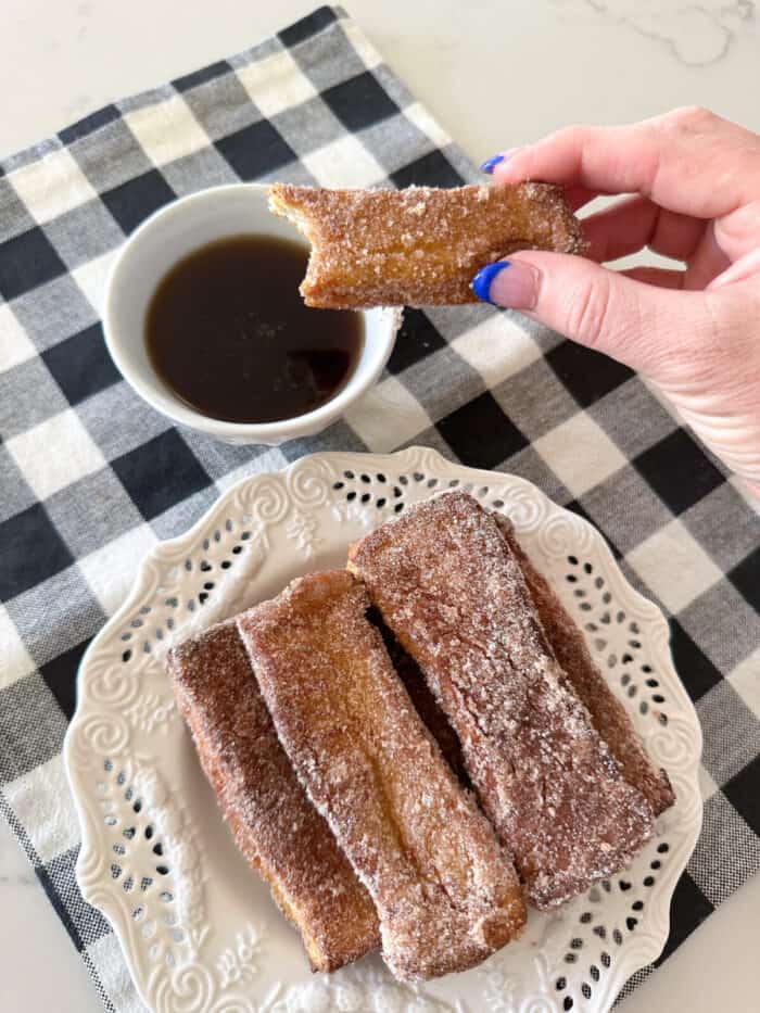 holding air fryer french toast stick over syrup