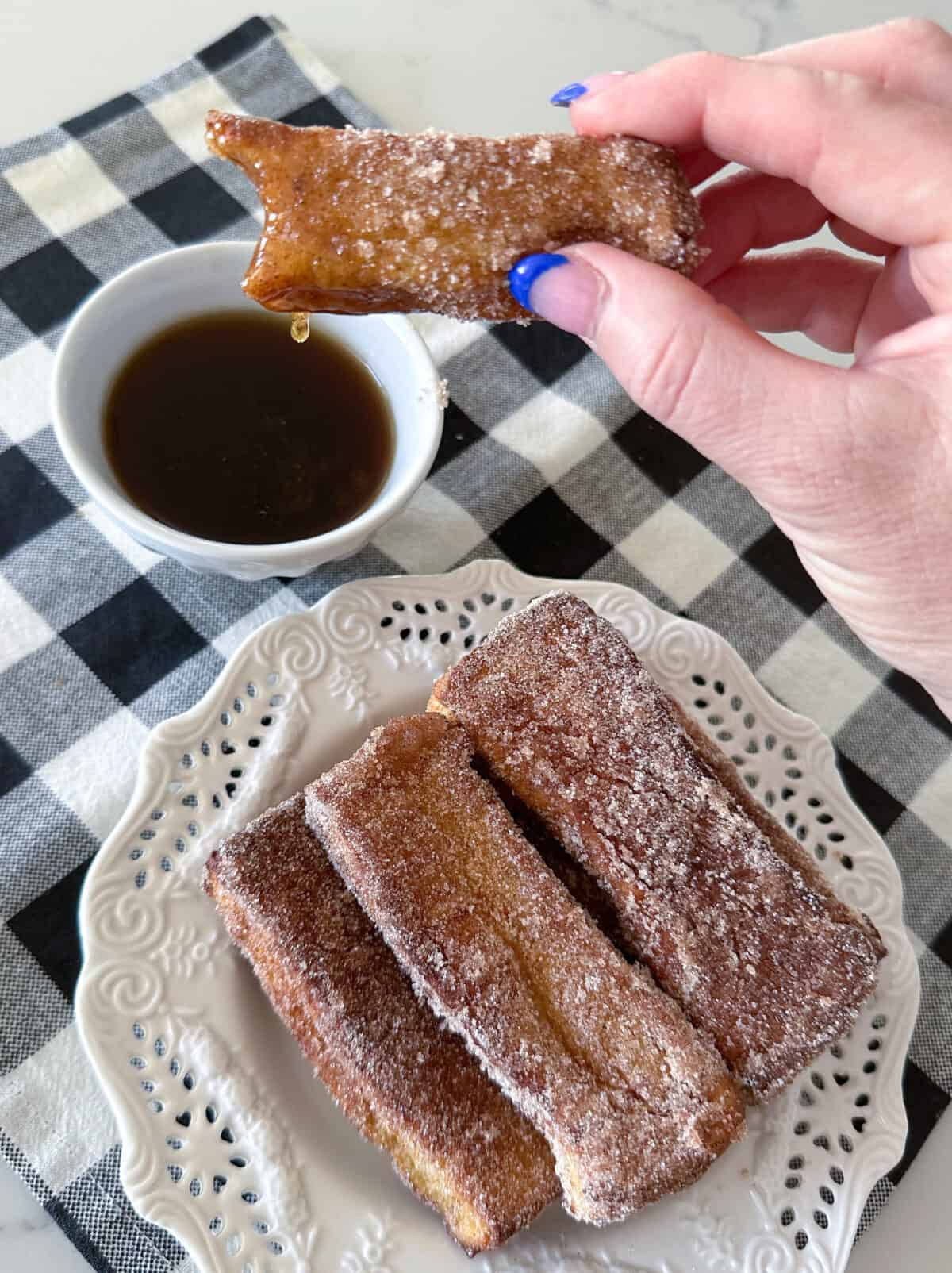 dipping air fryer french toast stick in syrup
