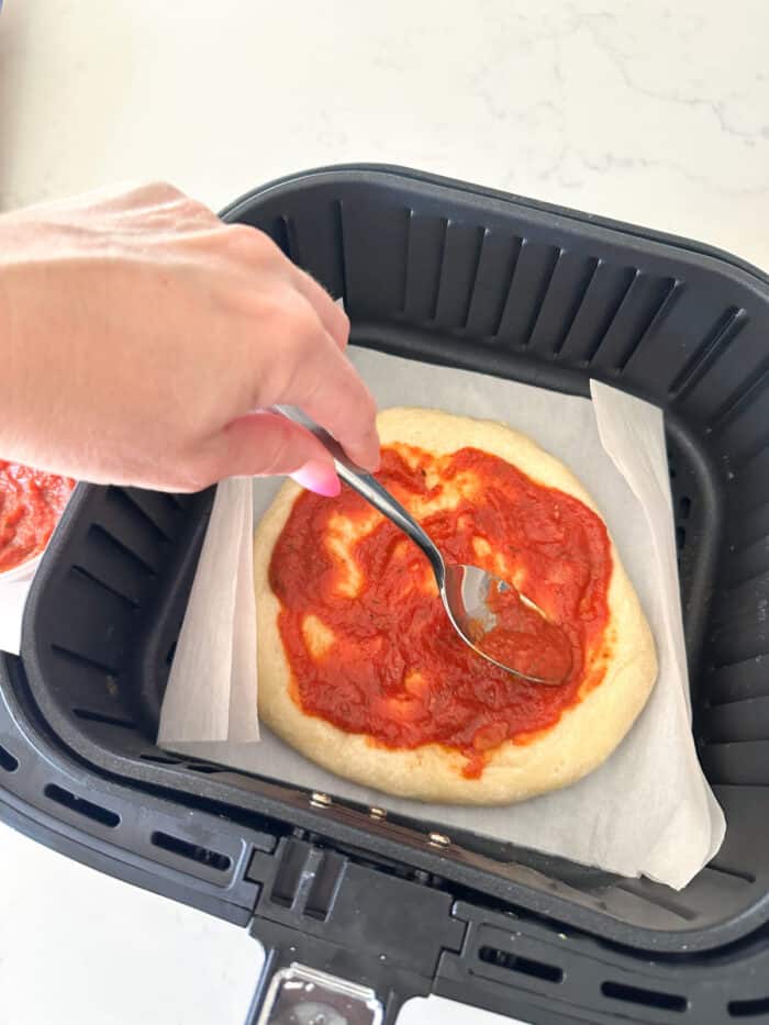 pizza crust with pizza sauce on top in air fryer