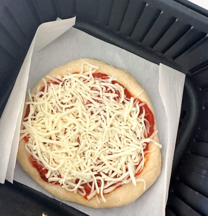uncooked pizza in air fryer basket