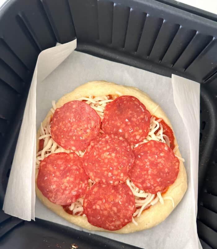 uncooked pizza in air fryer basket