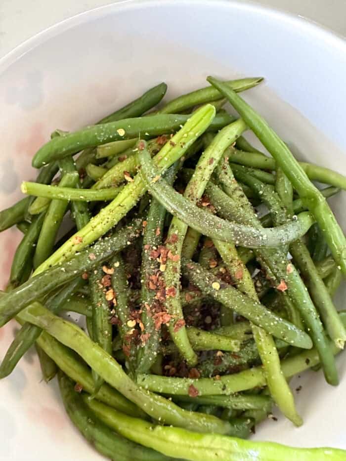 green beans in mixing bowl with seasonings