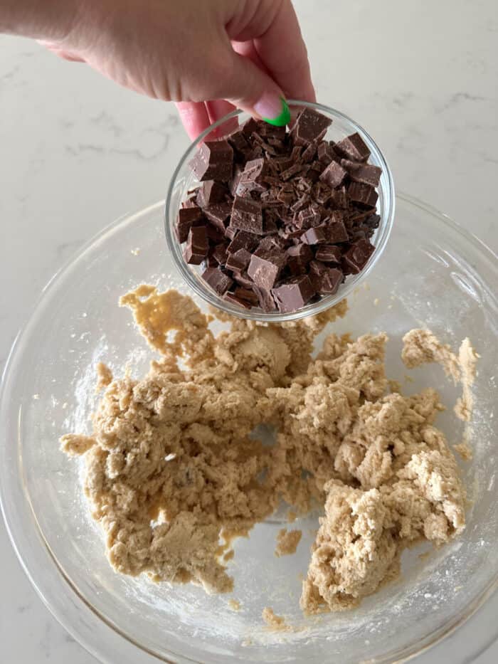 adding chocolate chunks to cookie dough