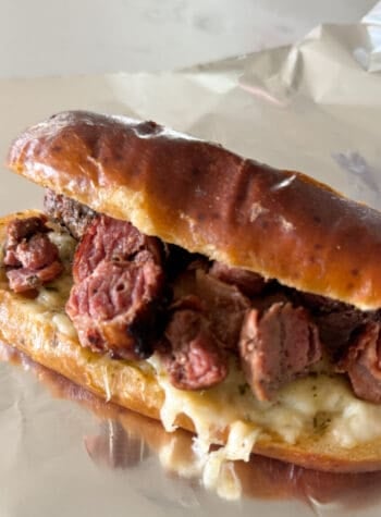 steak sandwich in cheesy garlic pretzel roll