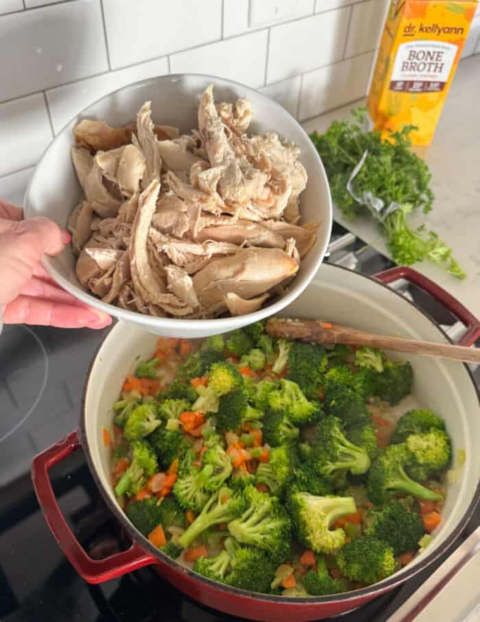 adding cooked shredded chicken to pot of sauteed vegetables