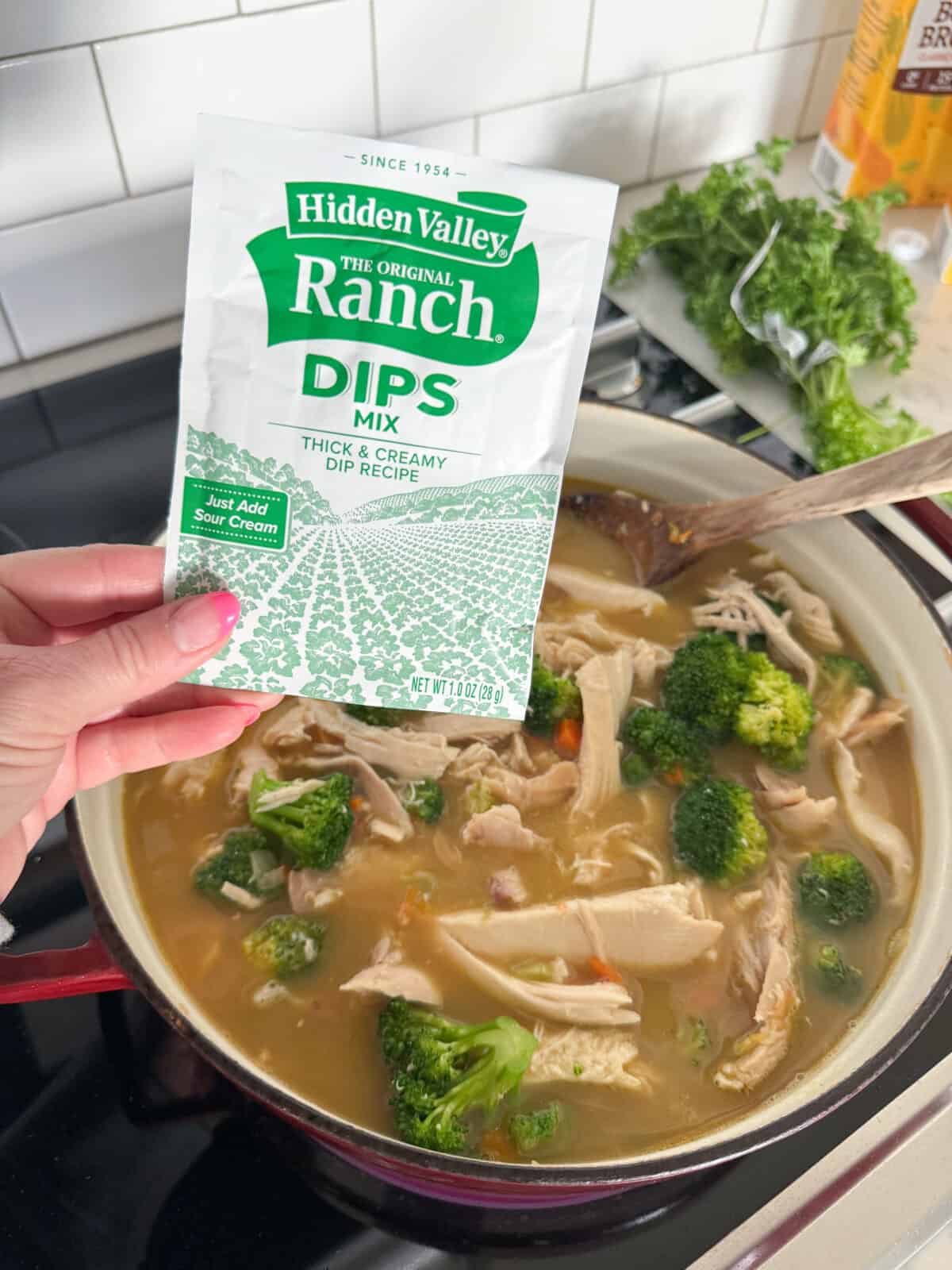 adding ranch seasoning to pot of chicken soup