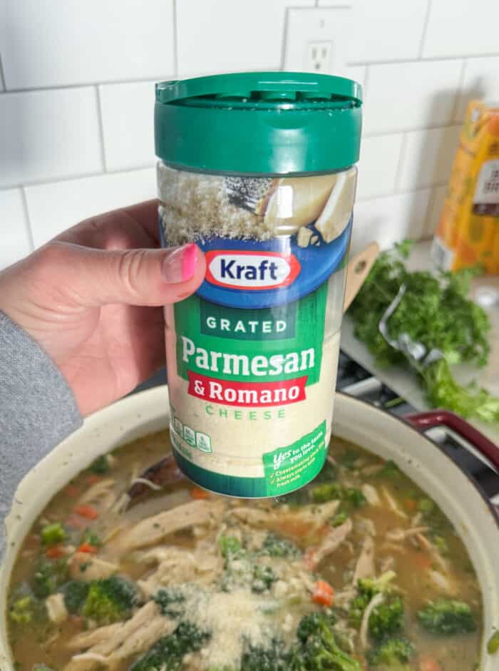 adding parmesan cheese to pot of chicken vegetable soup