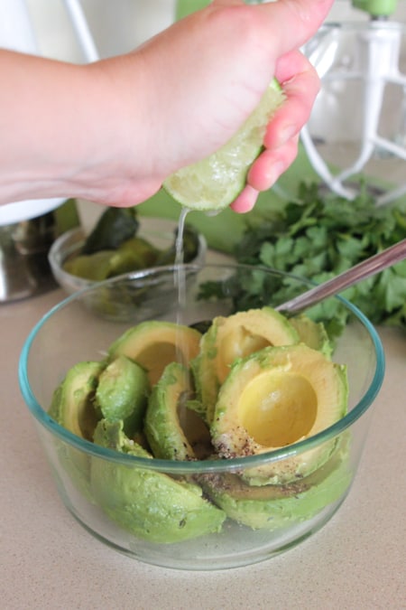 squeezing lime into bowl of avocados