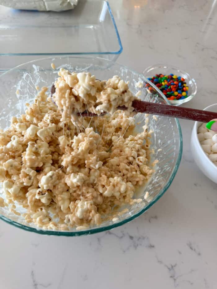 mixing popcorn rice crispy treats in mixing bowl